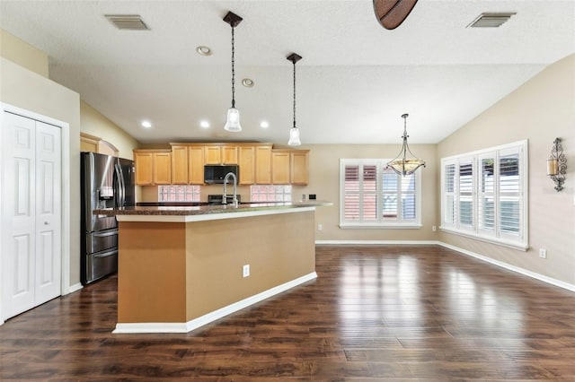 kitchen with light brown cabinetry, visible vents, stainless steel appliances, and vaulted ceiling