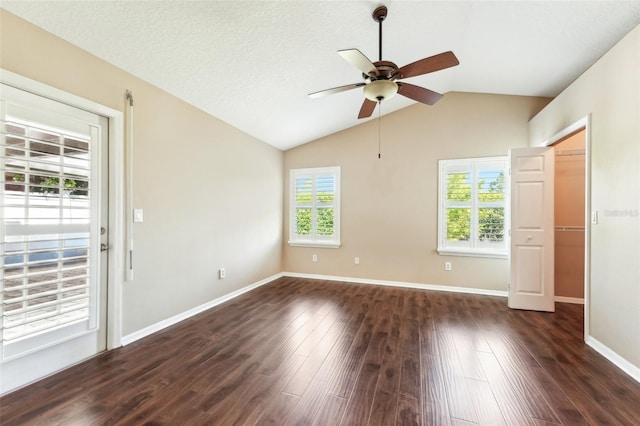 unfurnished room with baseboards, ceiling fan, lofted ceiling, a textured ceiling, and dark wood-style flooring