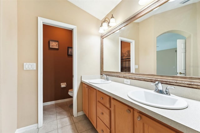 bathroom with tile patterned floors, double vanity, toilet, and a sink