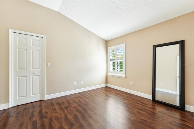 spare room featuring baseboards, lofted ceiling, a textured ceiling, and dark wood finished floors