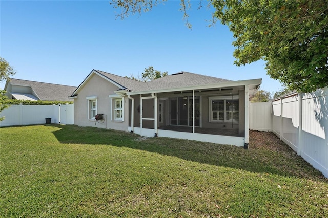 rear view of house with a yard, a fenced backyard, a sunroom, and stucco siding