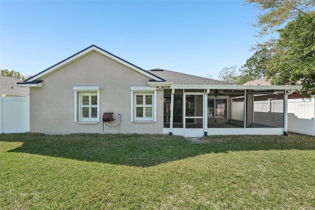 back of property with a yard, fence, and stucco siding