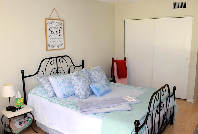 bedroom featuring visible vents, a closet, and wood finished floors