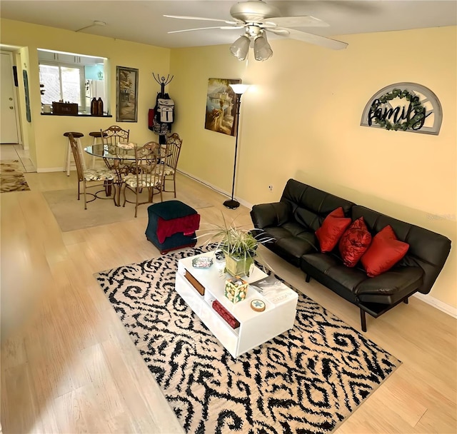 living room with baseboards, a ceiling fan, and wood finished floors