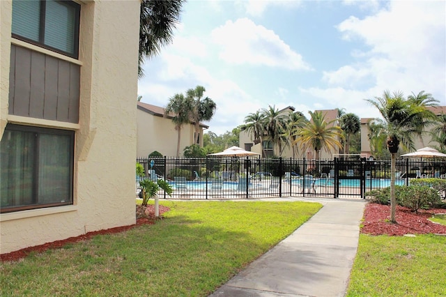 view of home's community with a yard, a swimming pool, and fence