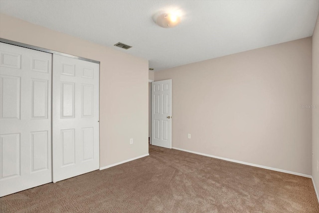 unfurnished bedroom with visible vents, baseboards, carpet, and a closet