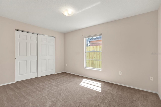 unfurnished bedroom featuring carpet, a closet, and baseboards