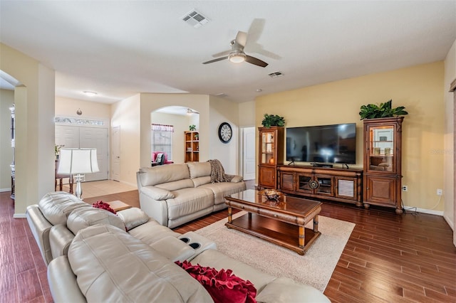 living room featuring visible vents, wood finished floors, arched walkways, baseboards, and ceiling fan