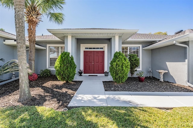 property entrance with a shingled roof and stucco siding