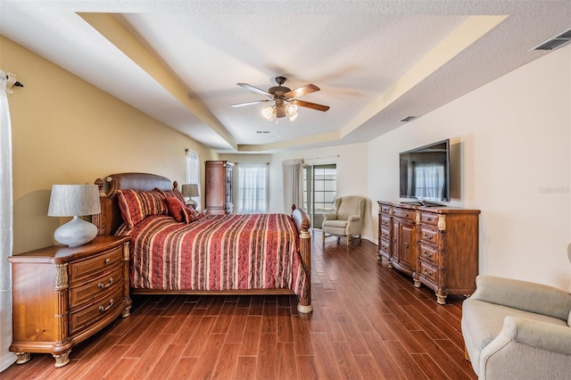 bedroom with visible vents, a raised ceiling, a textured ceiling, and wood finished floors