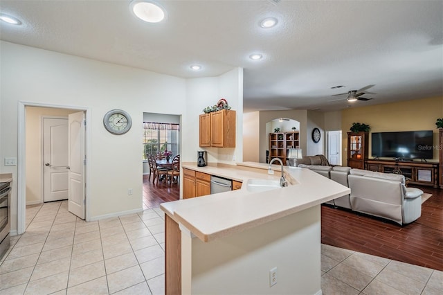 kitchen with a peninsula, arched walkways, a sink, light countertops, and appliances with stainless steel finishes