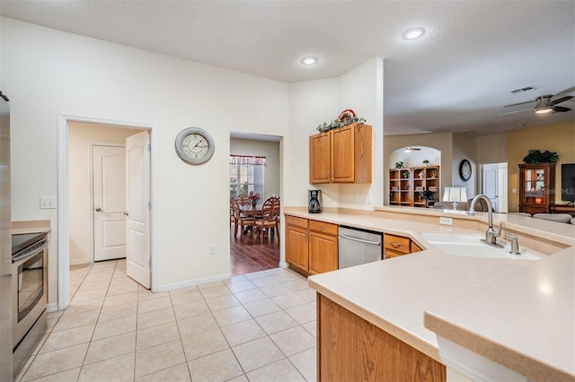 kitchen featuring light tile patterned flooring, arched walkways, a sink, light countertops, and appliances with stainless steel finishes