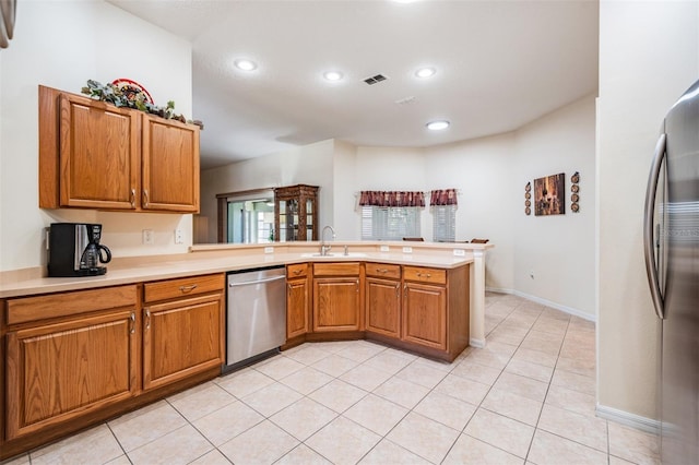 kitchen featuring visible vents, light countertops, brown cabinets, a peninsula, and stainless steel appliances