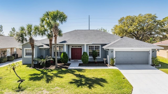 ranch-style house with concrete driveway, an attached garage, a front lawn, and central AC