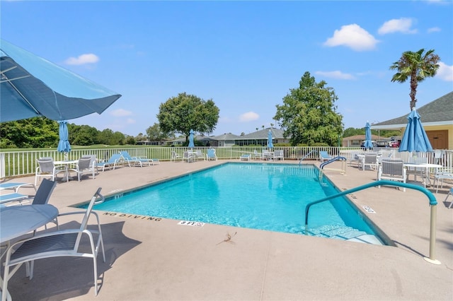 community pool with a patio and fence