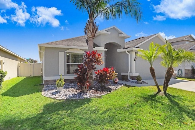 single story home featuring a front yard, an attached garage, fence, and stucco siding