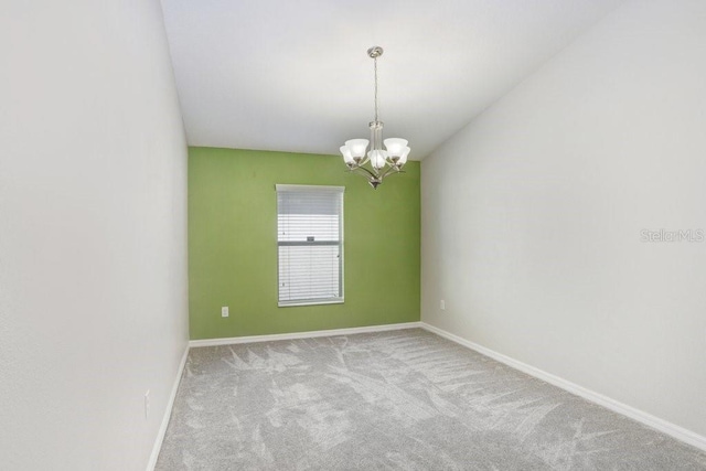 empty room with baseboards, an inviting chandelier, and carpet floors