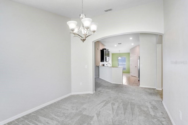 unfurnished room featuring visible vents, baseboards, light carpet, arched walkways, and a notable chandelier