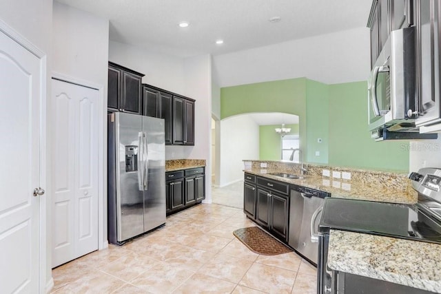 kitchen featuring a chandelier, vaulted ceiling, arched walkways, stainless steel appliances, and a sink