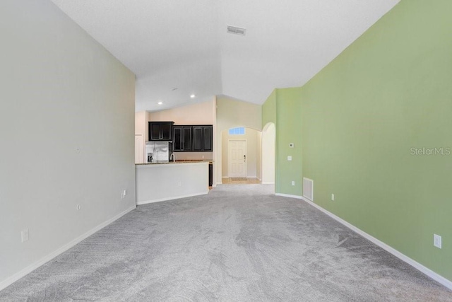 unfurnished living room featuring visible vents, arched walkways, baseboards, and vaulted ceiling