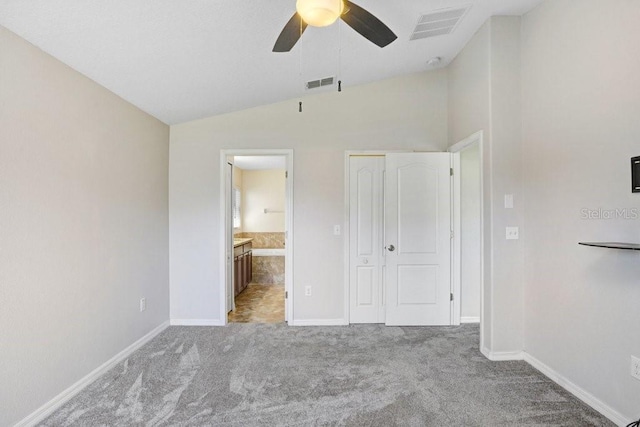 unfurnished bedroom featuring visible vents, ensuite bath, carpet flooring, and vaulted ceiling