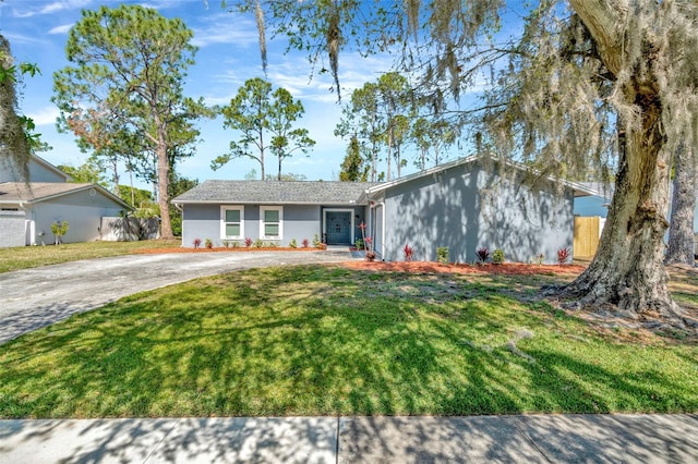 view of front of home featuring stucco siding, concrete driveway, a front yard, and fence