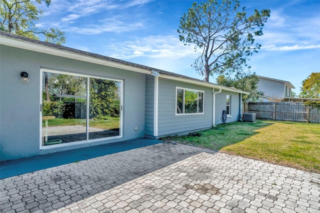 back of property featuring central air condition unit, stucco siding, a lawn, fence, and a patio area