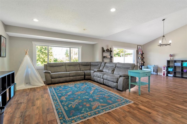 living area with a notable chandelier, a textured ceiling, lofted ceiling, and wood finished floors