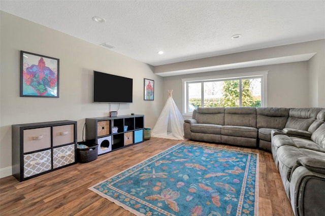 living room with recessed lighting, visible vents, a textured ceiling, and wood finished floors