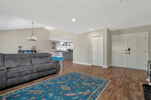 living room with wood finished floors, baseboards, vaulted ceiling, a textured ceiling, and a chandelier