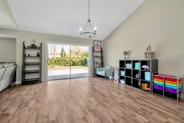 recreation room featuring a notable chandelier, baseboards, lofted ceiling, and wood finished floors