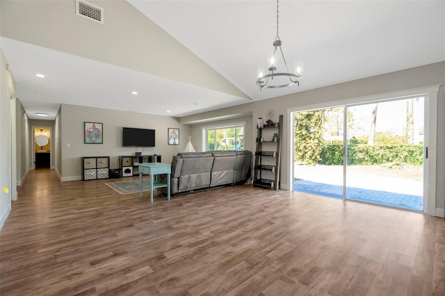 living area featuring visible vents, baseboards, lofted ceiling, wood finished floors, and a notable chandelier