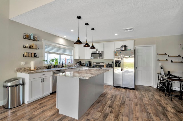 kitchen featuring visible vents, a kitchen island, dark wood finished floors, white cabinetry, and stainless steel appliances