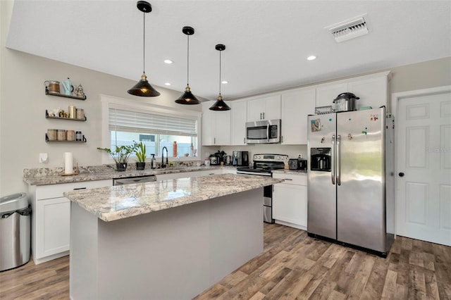 kitchen featuring visible vents, a center island, appliances with stainless steel finishes, light wood-style floors, and white cabinetry