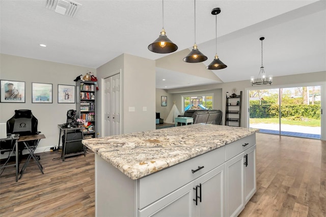 kitchen with hanging light fixtures, light wood-style flooring, and visible vents