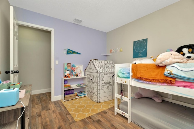 bedroom featuring visible vents, baseboards, and wood finished floors