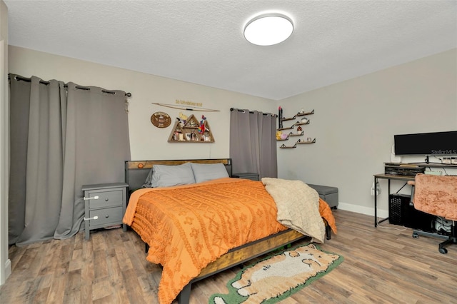 bedroom with wood finished floors, baseboards, and a textured ceiling