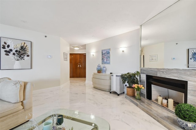 living area with baseboards, marble finish floor, and a high end fireplace