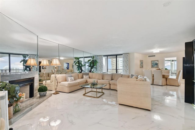 living room with floor to ceiling windows, visible vents, marble finish floor, and a fireplace