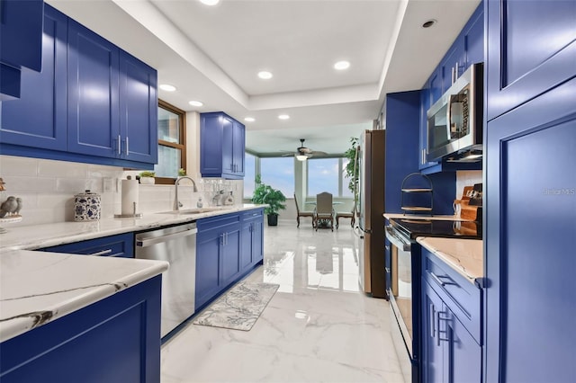 kitchen featuring a sink, blue cabinetry, a raised ceiling, and appliances with stainless steel finishes