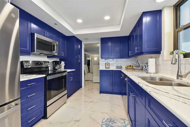 kitchen featuring backsplash, marble finish floor, stainless steel appliances, a raised ceiling, and a sink