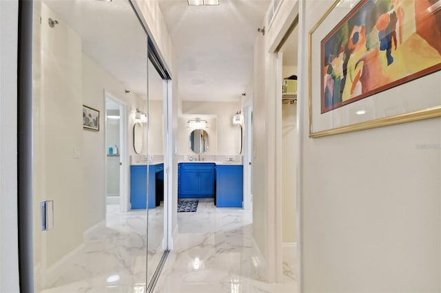 hallway with baseboards, marble finish floor, and a sink