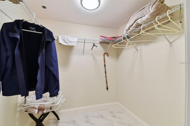 walk in closet featuring marble finish floor