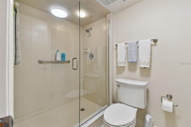 bathroom with a shower stall, toilet, and visible vents