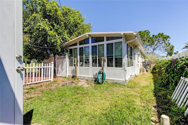 back of house with a yard, a sunroom, central air condition unit, and fence