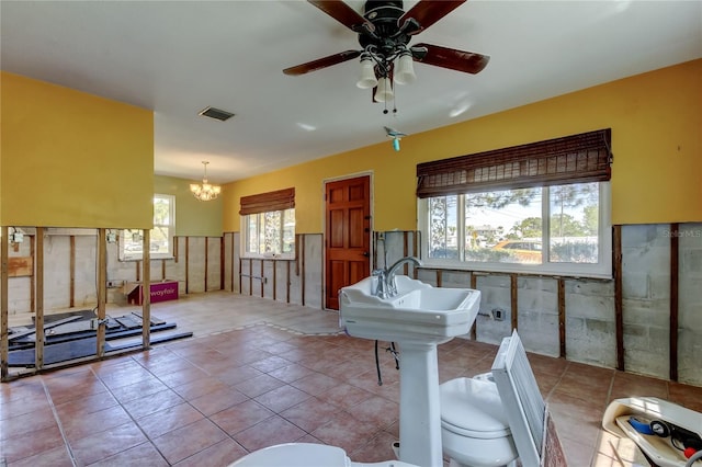 interior space featuring visible vents, tile patterned flooring, wainscoting, and ceiling fan with notable chandelier