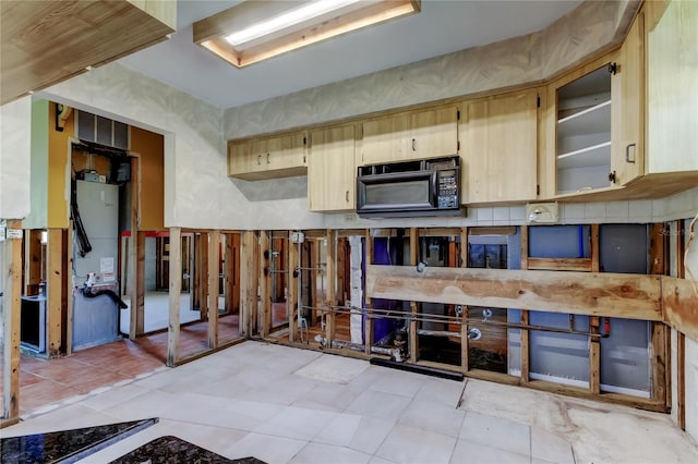 kitchen with light brown cabinets and black microwave