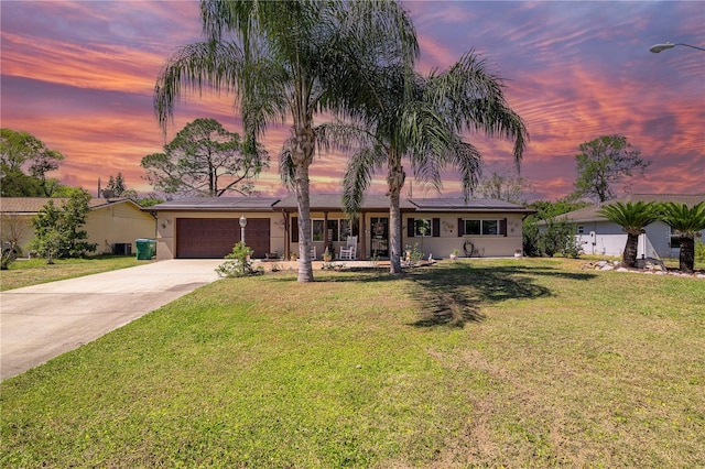 ranch-style house with solar panels, a front yard, an attached garage, and driveway