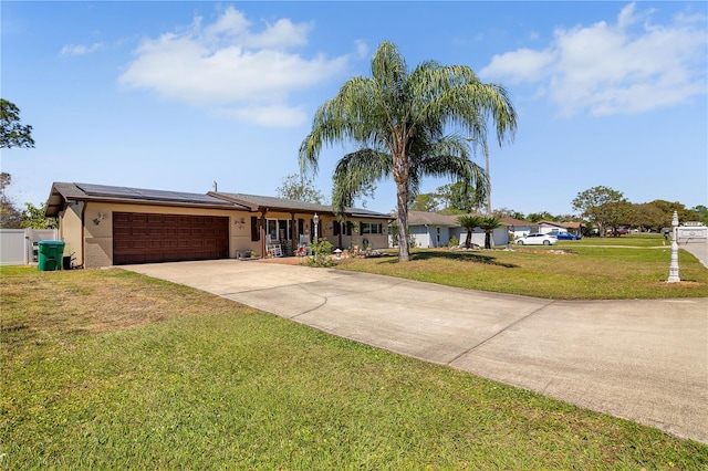 ranch-style house featuring solar panels, concrete driveway, a front yard, stucco siding, and a garage