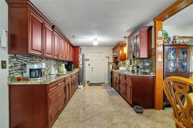 kitchen with visible vents, dark brown cabinets, light stone countertops, and a sink